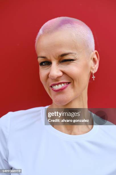 mid adult woman with short hair blinking an eye to camera - special hair stock pictures, royalty-free photos & images