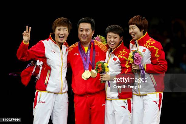 Gold medalists Ning Ding , Yue Guo and Xiaoxia Li of China celebrate on the podium after putting their gold medals around the neck of head coach Shi...