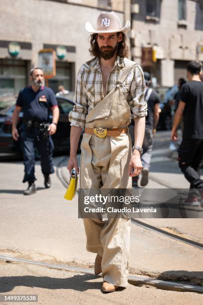 Guest is seen wearing beige cow-boy hat, printed shirt, a beige salopette, and a yellow handbag outside Dolce & Gabbana during the Milan Fashion Week...