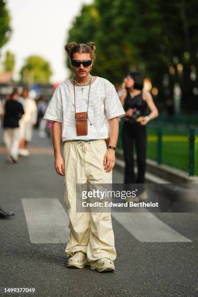 Guest wears black sunglasses, blue pearls necklaces, a camel shiny leather necklace bag from Celine, a beige zebra print pattern t-shirt, pale yellow...
