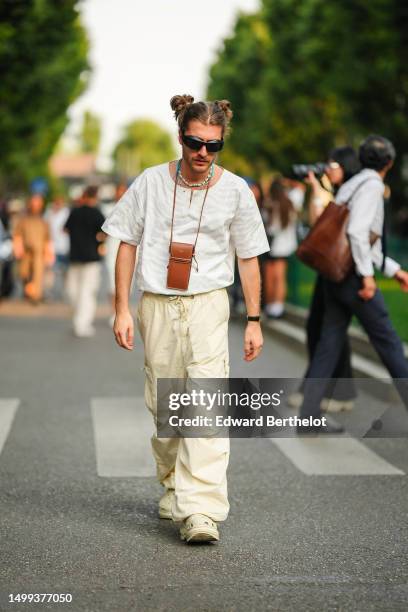 Guest wears black sunglasses, blue pearls necklaces, a camel shiny leather necklace bag from Celine, a beige zebra print pattern t-shirt, pale yellow...