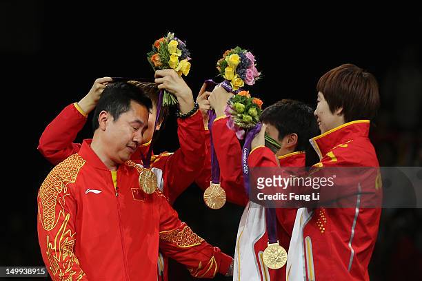 Gold medalists Ning Ding , Yue Guo and Xiaoxia Li of China celebrate on the podium by putting their gold medals around the neck of head coach Shi...
