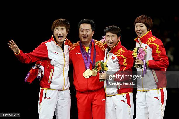 Gold medalists Ning Ding , Yue Guo and Xiaoxia Li of China celebrate on the podium after putting their gold medals around the neck of head coach Shi...