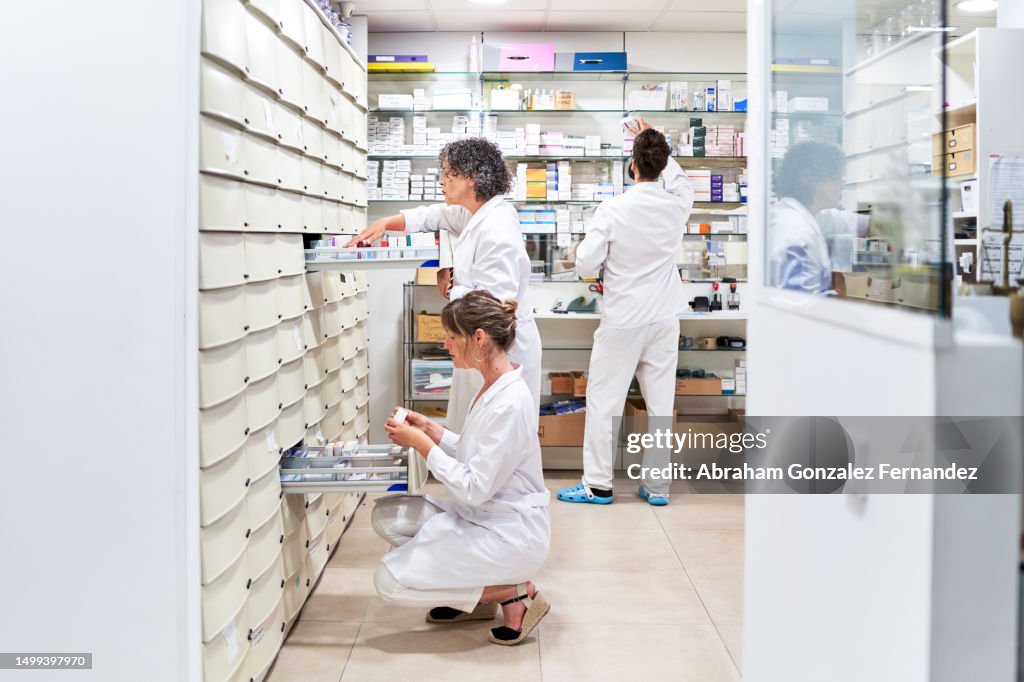 Staff looking for medicines in drawers of a pharmacy store