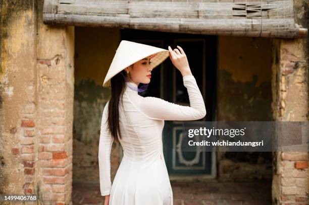 happy vietnamese girl in traditional white ao dai dress with vietnamese hat - da nang stock pictures, royalty-free photos & images