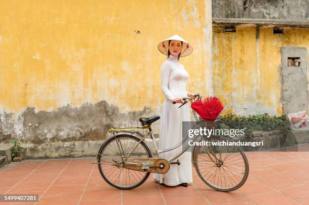 happy vietnamese girl in traditional white ao dai dress with vietnamese hat - hoi an stockfoto's en -beelden