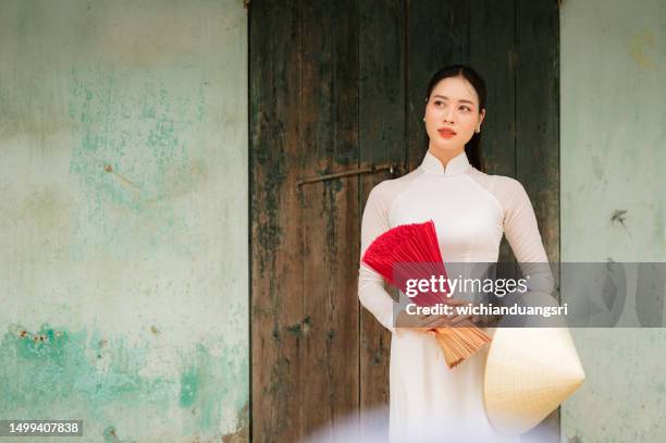 happy vietnamese girl in traditional white ao dai dress with vietnamese hat - vietnam woman stock pictures, royalty-free photos & images