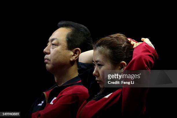 Ai Fukuhara of Japan and Japanese head coach Yasukazu Murakami watch teammates take on China in the third match during the Women's Team Table Tennis...