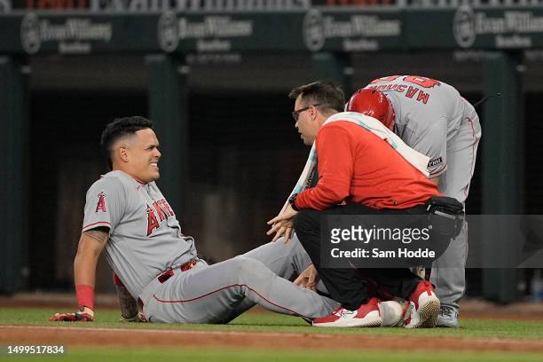 Gio Urshela of the Los Angeles Angels is tended to by a trainer after the top of the first inning of the game against the Texas Rangers at Globe Life...