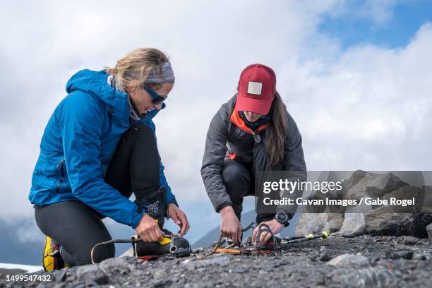 a female mountaineer explains how to put on cramp ons at base camp, mt. baker - basislager stock-fotos und bilder