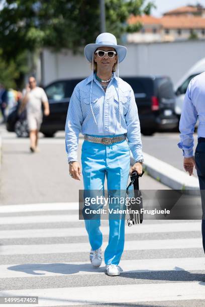 Ulisses de Melo is seen wearing a white cow boy hat, white sunglasses, a white and blue necklace, a Prada necklace, a white and blue checked...