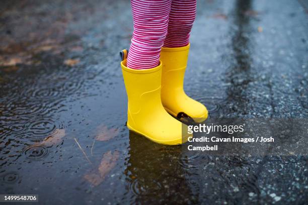 a close of up a child's rain boots in a puddle - kway photos et images de collection