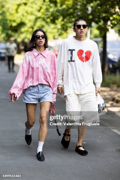 Guests are seen wearing on the left black sunglasses, a pink and white long-sleeved shirt with stars printed on, denim shorts, white socks, black...
