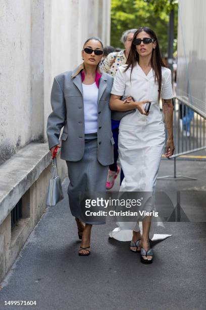 Amina Muaddi wears grey blazer, skirt & Gilda Ambrosio wears white dress outside Prada during the Milan Fashion Week - Menswear Spring/Summer 2024 on...