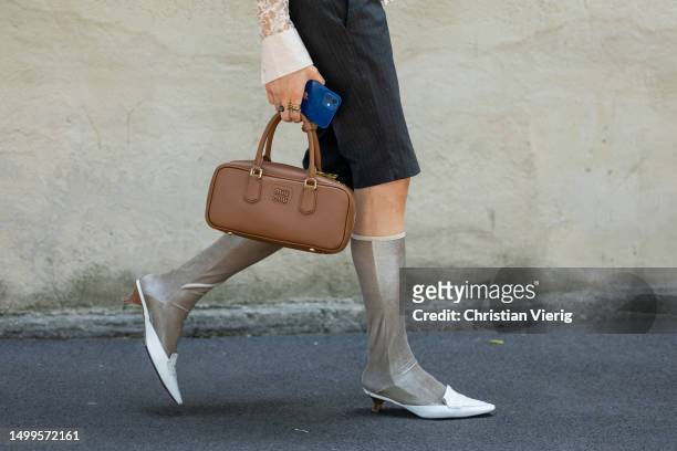 Guest wears brown Miu Miu bag, beige jumper, shorts, knee high socks, white loafers outside Prada during the Milan Fashion Week - Menswear...