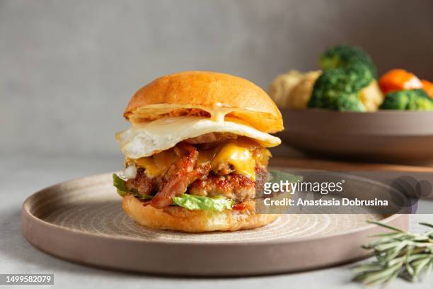 crispy chicken burger with cheese, bacon and fried egg. close up. - plate side view stock pictures, royalty-free photos & images