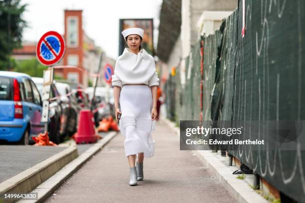 Gloria Wen wears a white felt / wool boat hat, a white ribbed wool high flowing neck / cropped pullover, a white ribbed wool embossed striped pattern...