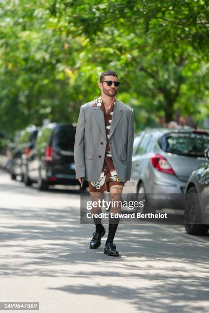 Pelayo Diaz wears black sunglasses from Ray Ban, diamonds earrings, a gold small chain with diamond pendant earrings, a dark brown with white / black...