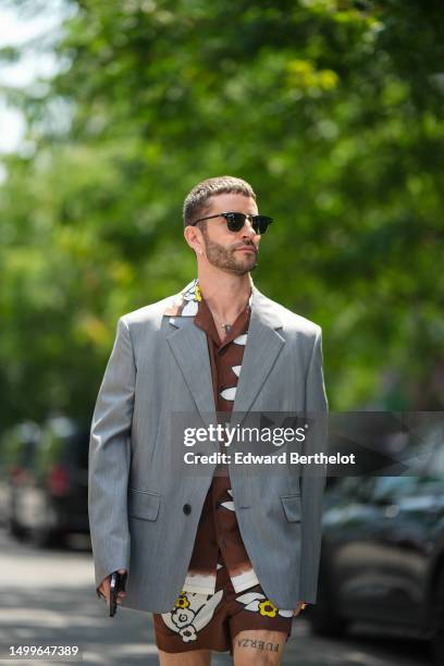 Pelayo Diaz wears black sunglasses from Ray Ban, diamonds earrings, a gold small chain with diamond pendant earrings, a dark brown with white / black...