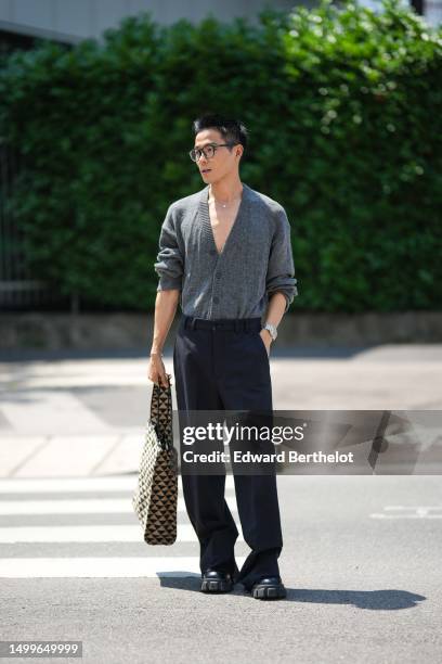 WeiRan Ji wears black glasses, a gray wool buttoned cardigan, a silver with diamond pendant necklace, a silver watch, a diamonds bracelet, black...