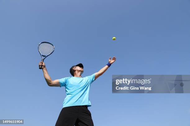 a tennis player serving on a tennis court - blue tennis racket stock pictures, royalty-free photos & images