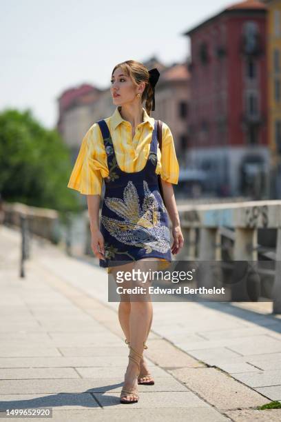 Cristine Sun wears gold earrings, a pale yellow with small white striped print pattern short sleeves shirt from Etro, a navy blue denim with...