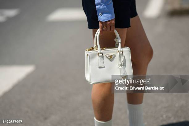 Cristine Sun wears a pale blue cropped shirt from Prada, a black shiny leather large belt, navy bleu suit shorts, a white latte matte leather...