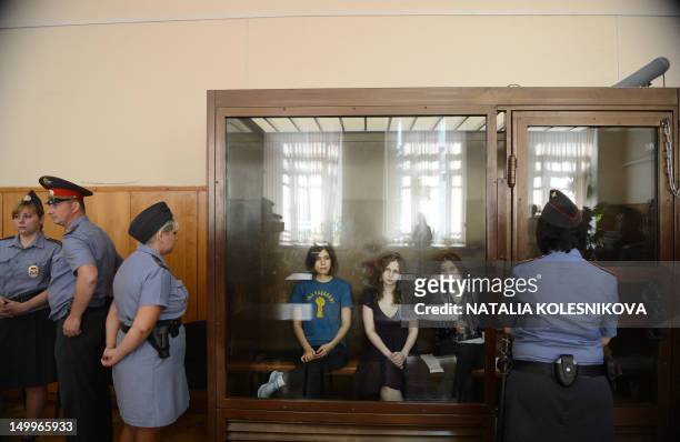 Members of a female punk band "Pussy Riot" Nadezhda Tolokonnikova , Maria Alyokhina and Yekaterina Samutsevich , sit inside a glass enclosure during...
