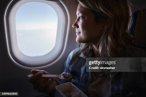 smiling woman having a snack during a flight by plane. - plane food stock pictures, royalty-free photos & images