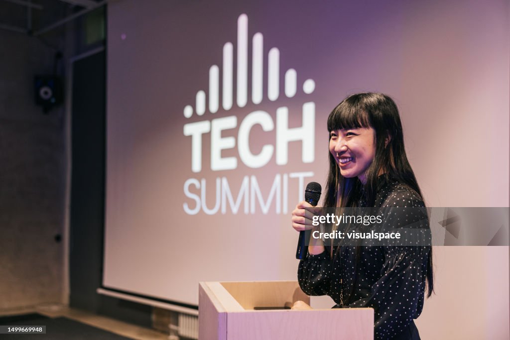 Japanese young businesswoman speaking with audience on Tech conference.
