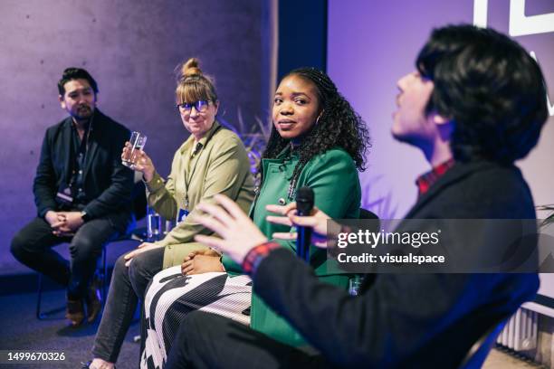 verschiedene geschäftsleute unterhalten sich während der podiumsdiskussion auf einer tech-konferenz. - lässig schicker stil stock-fotos und bilder