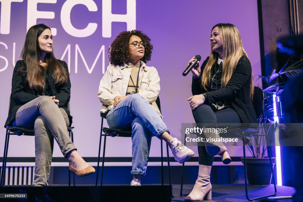 Gruppe multiethnischer Geschäftsfrauen, die eine großartige Podiumsdiskussion auf der Bühne machen.