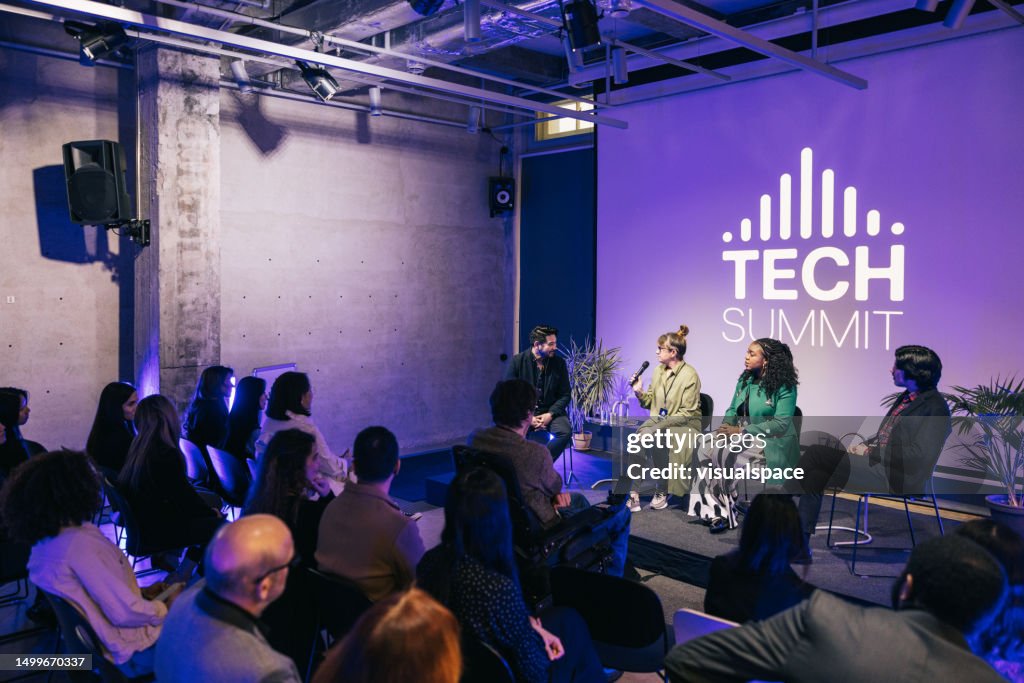 Diverse audience listening closely to lively panel discussion at tech conference.
