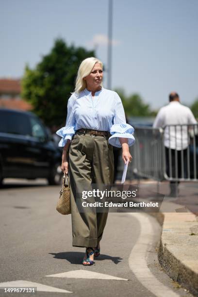 Guest wears a white and blue striped print pattern shirt with embroidered ruffled wrists details, a dark brown shiny leather belt, khaki brown large...