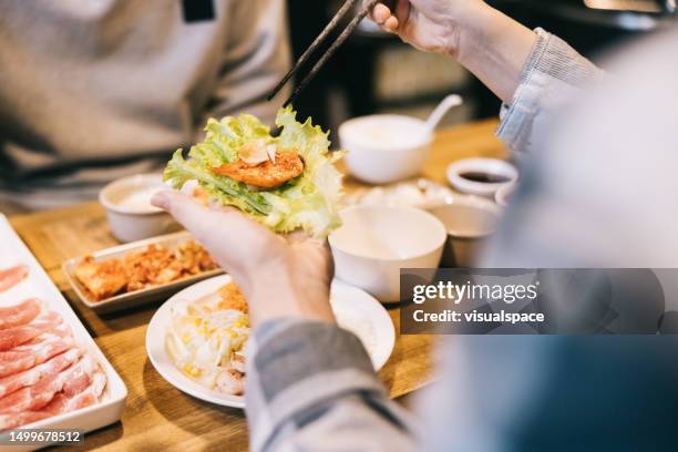 friends enjoying korean bbq and side dishes at a local restaurant. - korean food stockfoto's en -beelden