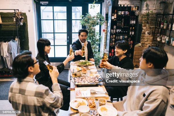 friends having a cheerful toast at local korean bbq restaurant. - korean ethnicity stock pictures, royalty-free photos & images