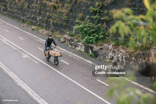 cargo bike courier delivering packages in helsinki - green economy stock pictures, royalty-free photos & images