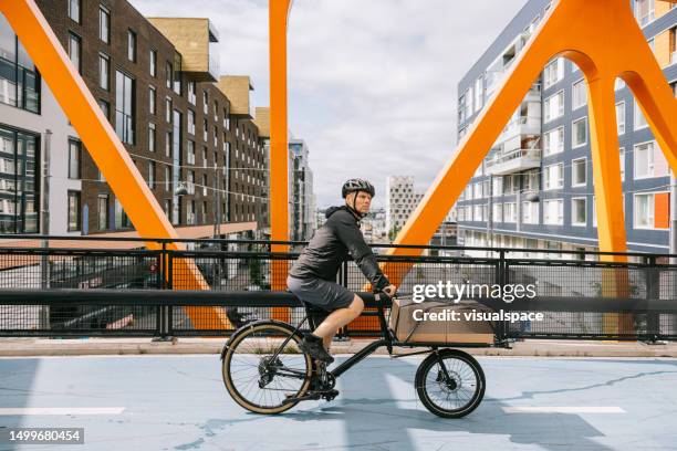 cargo bike courier riding through the city with a loaded bike - finland stock pictures, royalty-free photos & images