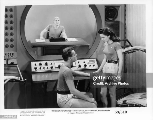 Ross Ford sitting before Donna Martell in control room in a scene from the film 'Project Moon Base', 1953.