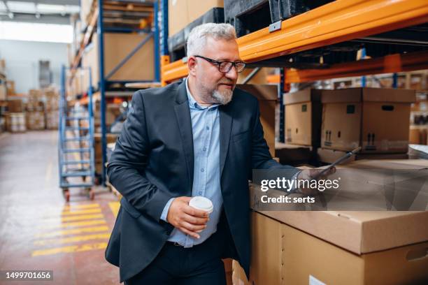 efficient factory management: portrait of smiling senior manager businessman or ceo using tablet to monitor production in industrial factory warehouse - diretor geral imagens e fotografias de stock