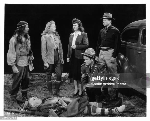 Charles Stevens, Evelyn Ankers, Ruth Hussey, Bruce Cabot, and Patrick McVey standing over a disabled Henry Travers in a scene from the film 'Pierre...