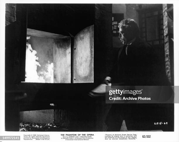 Herbert Lom throwing documents into fire in a scene from the film 'The Phantom Of The Opera', 1962.