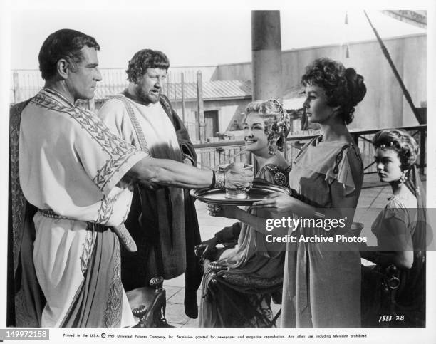 Laurence Olivier is served wine by Jean Simmons as Peter Ustinov, Nina Foch, and Joanna Barnes watch in a scene from the film 'Spartacus', 1960.