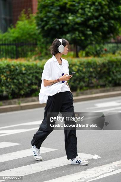 Guest wears white headphones, a white short sleeves / oversized shirt, black suit pants, white fabric and navy blue logo leather details sneakers...