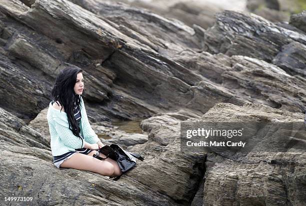 Woman sat on rocks watches the Relentless Boardmasters pro-surfing competition on August 8, 2012 in Newquay, England. The 6 Star Event, part of a...