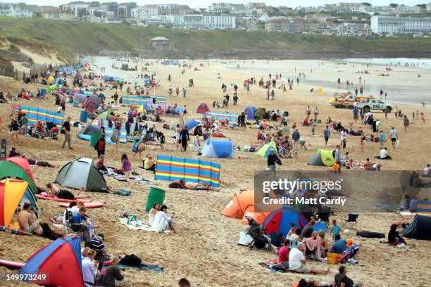 People gather on the beach as surfers compete in a heat during the Relentless Boardmasters pro-surfing competition on Fistral Beach on August 8, 2012...