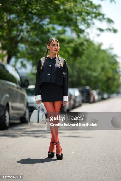 Guest wears diamond earrings, a black with embroidered rhinestones buttoned jacket, a black short skirt, red mesh / fishnet tights, a white with...