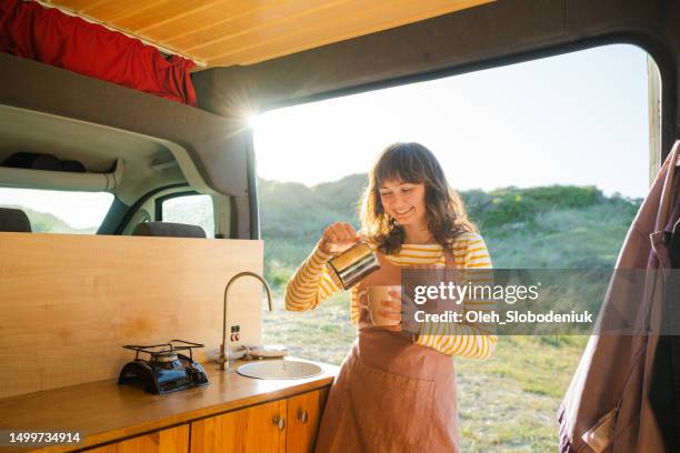 woman in apron drinking coffee in  the camper van - camper van imagens e fotografias de stock