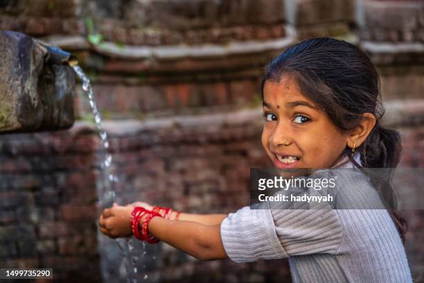 junges nepalesisches mädchen, das aus dem stadtbrunnen auf dem durbar square trinkt - hands fountain water stock-fotos und bilder