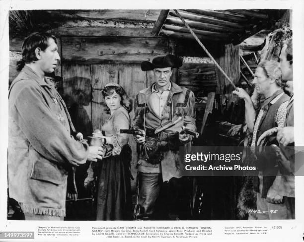 Mike Mazurki has gun pulled on him and his men by Gary Cooper as Paulette Goddard watches in a scene from the film 'Unconquered', 1947.